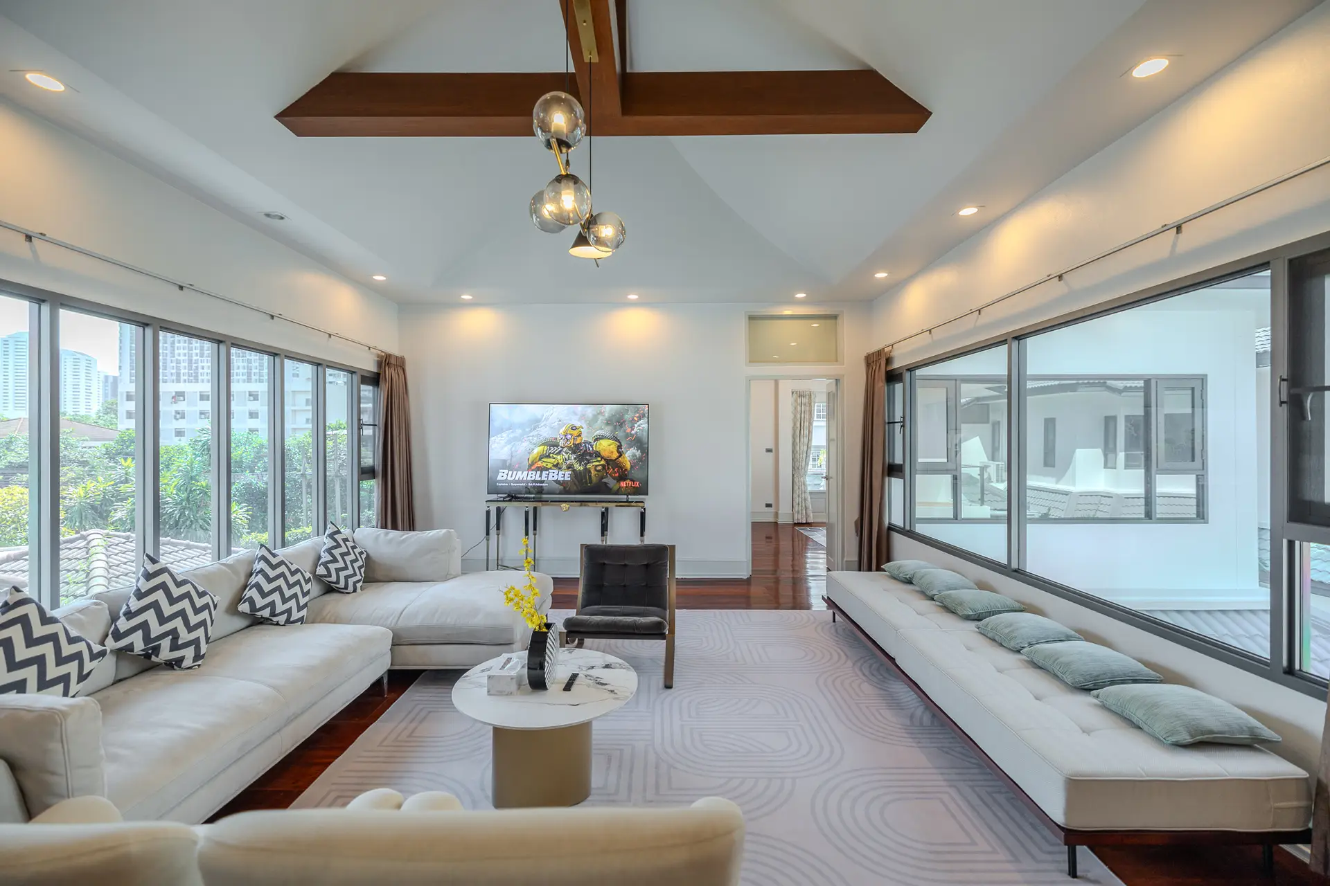 Upper-floor lounge with an L-shaped sofa and wide windows at Villa Oasis