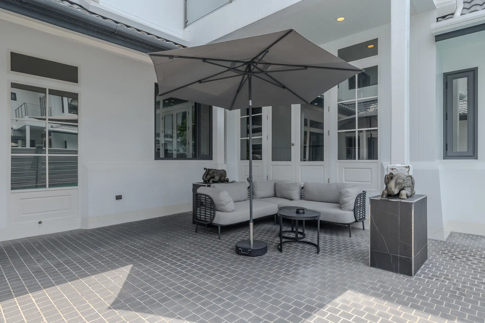 Covered terrace with sofa seating and umbrella at Villa Noir