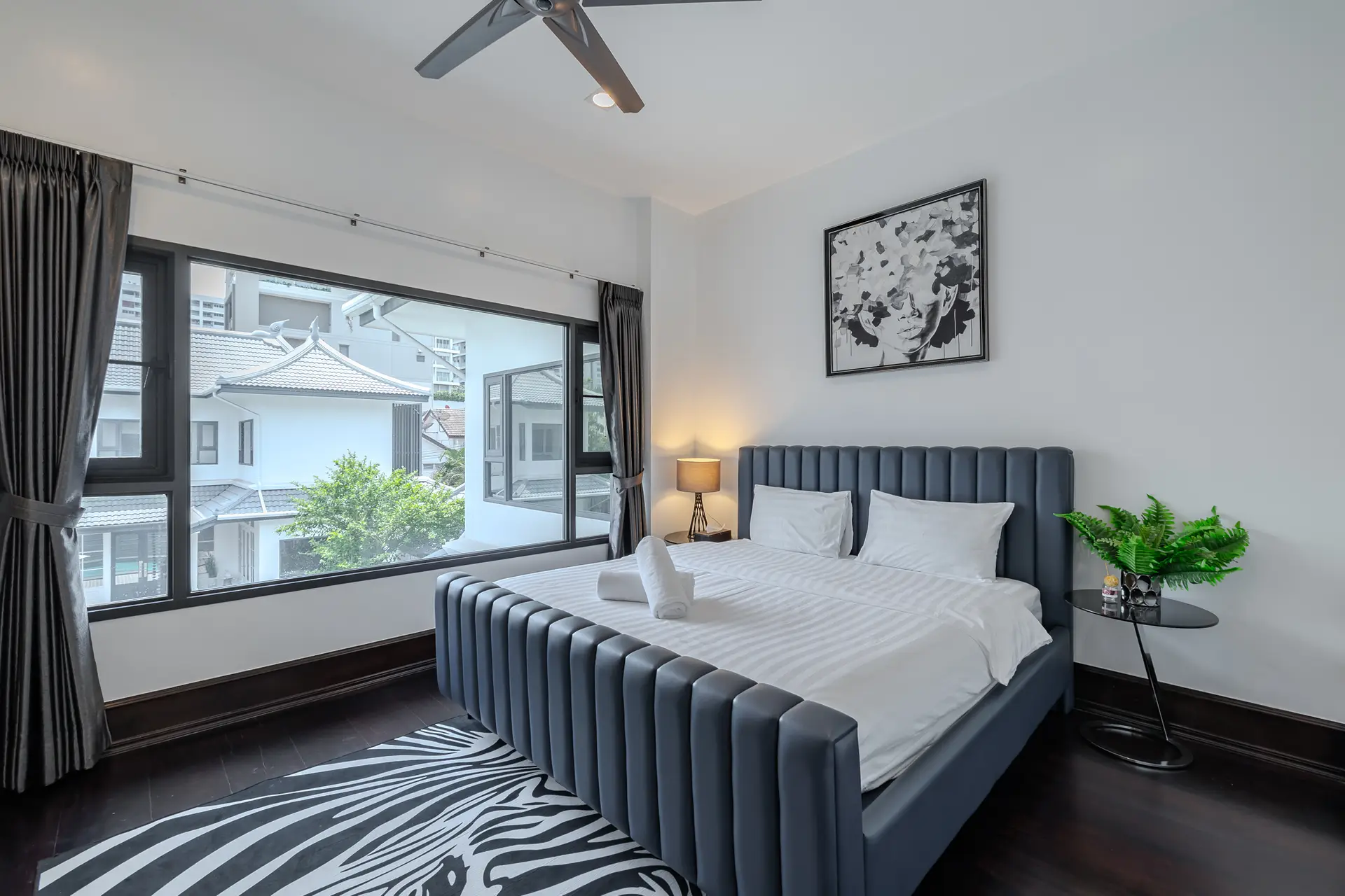 Bedroom with a dark upholstered bed and zebra-print rug at Villa Noir