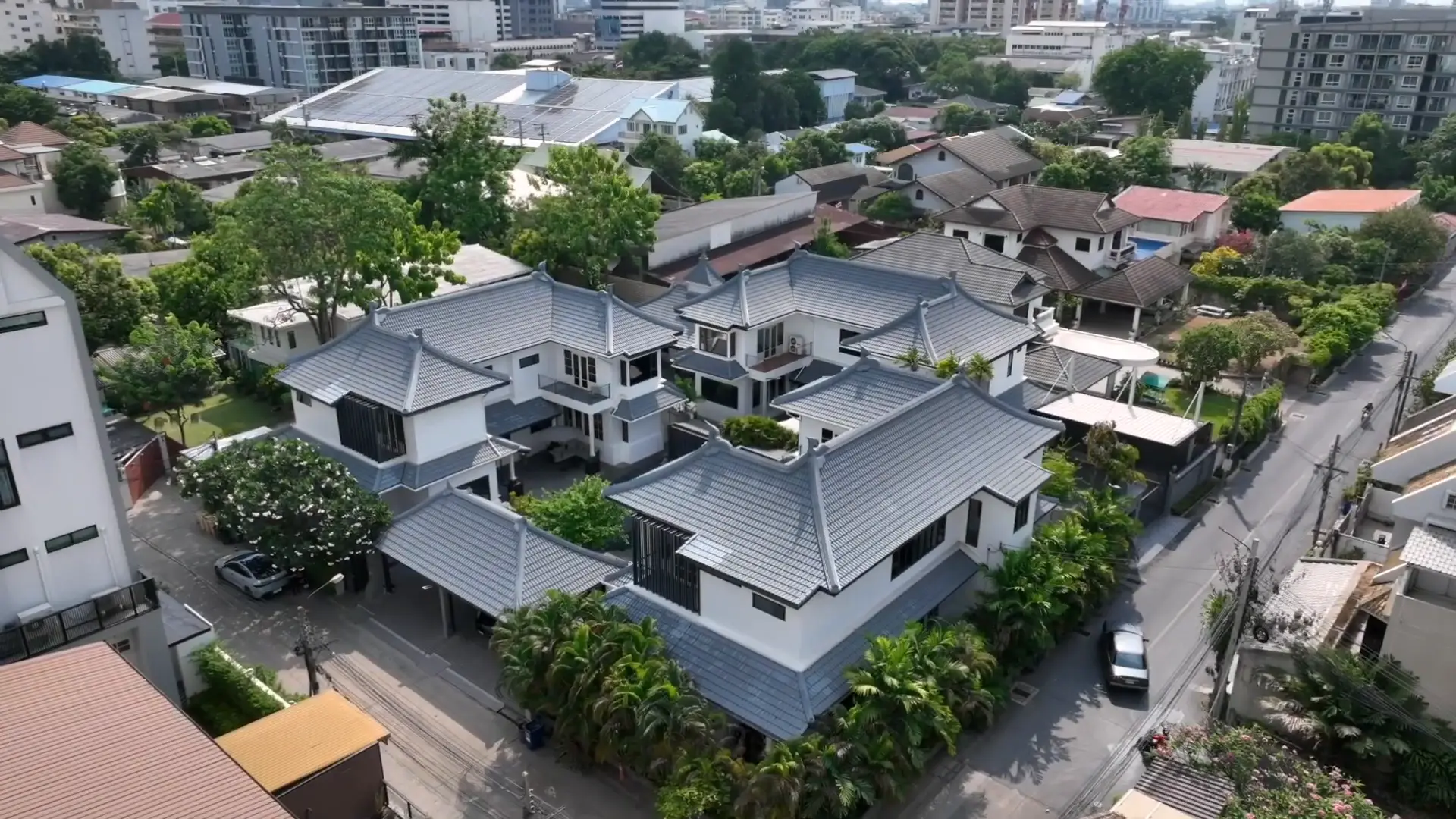 Aerial view of the three villas and their grey tiled roofs among the trees of Thong Lo, Bangkok
